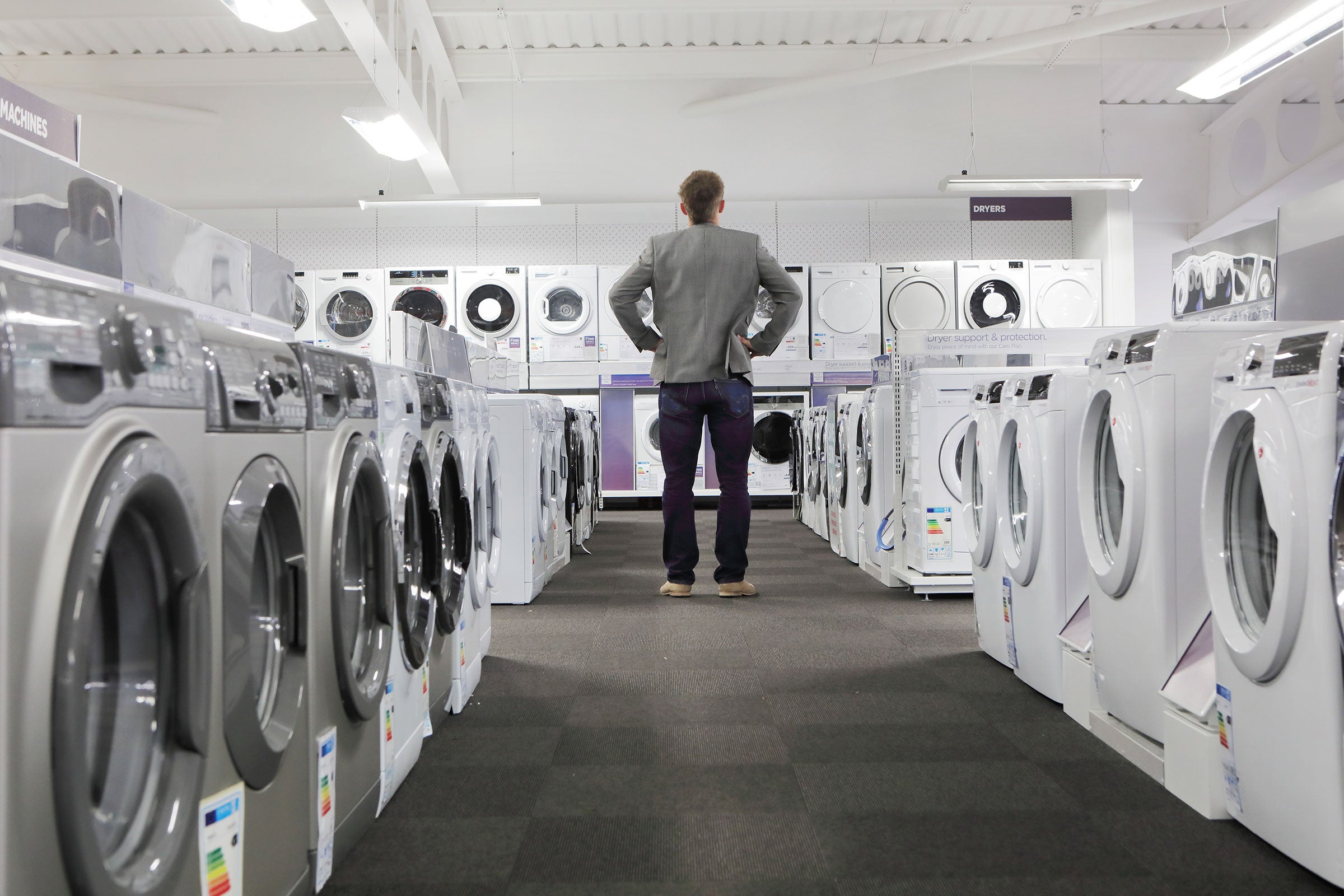 A person looking at many washers and dryers